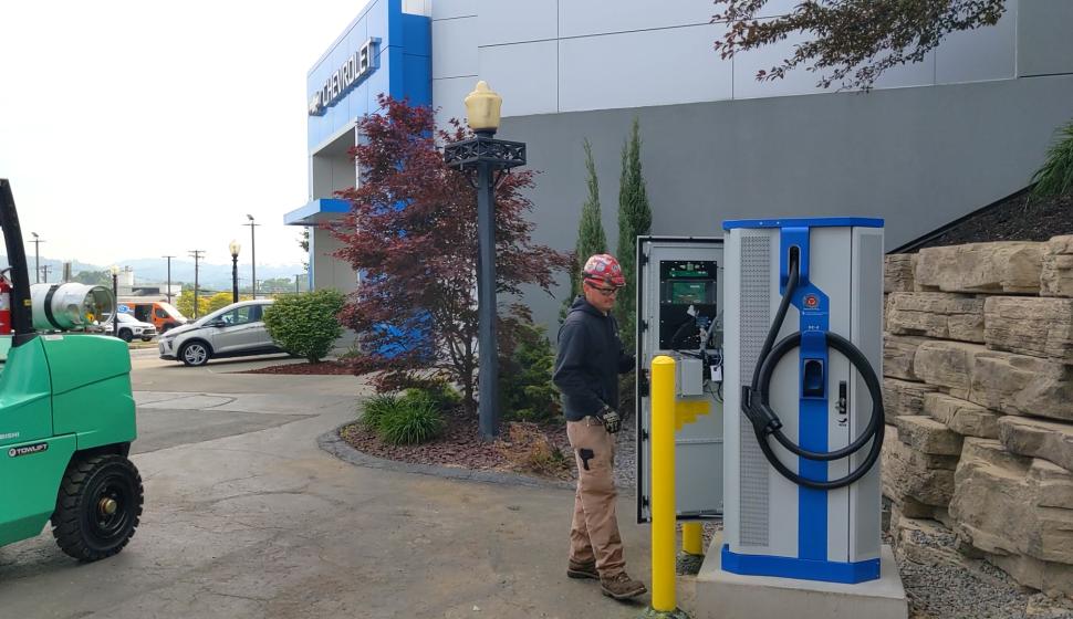 Electrician inspects newly installed exterior commercial Level 3 DC Fast Charging EV charger