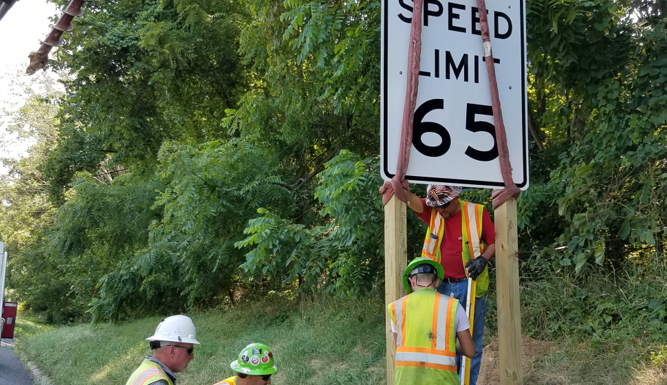A team sets and installs a temporary speed limit sign