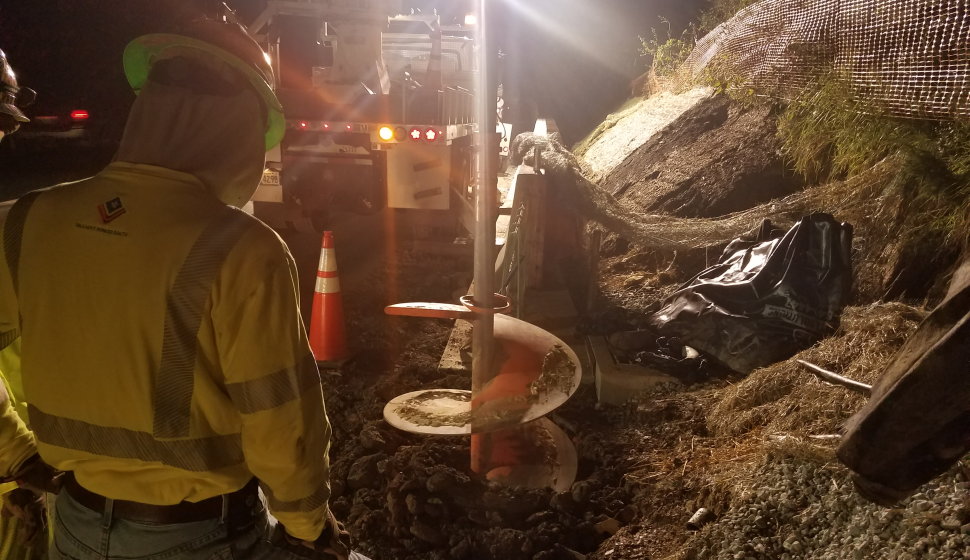 Crews work at night, drilling holes for highway lighting foundations