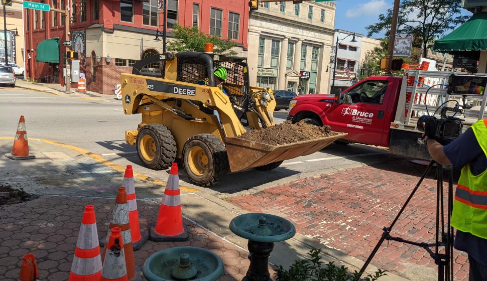 Construction worker drives skid steer over brick road