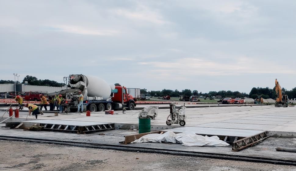 Construction team installing concrete pads around airport terminal