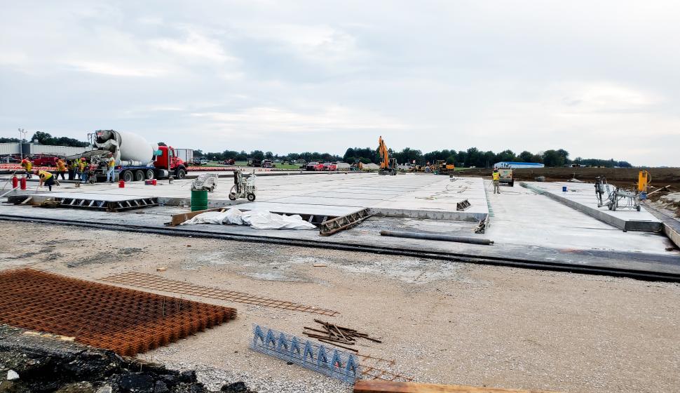 Wide shot of construction installing concrete pads around airport terminal