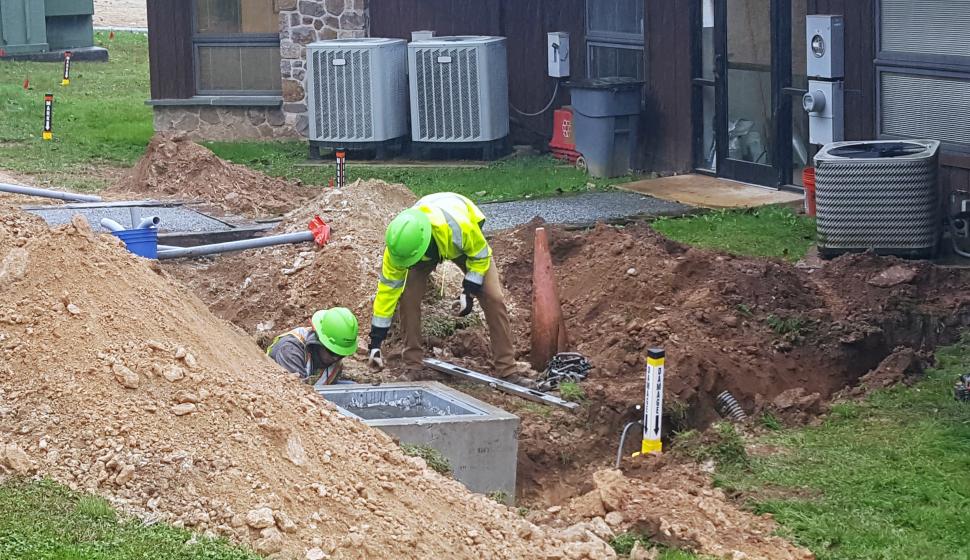 Highway construction workers beside open, unburied vault