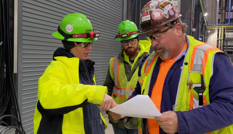 Foreman and electricians consult schematics