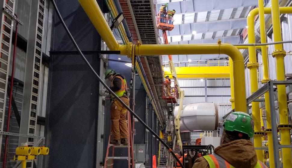 Electricians on multiple lifts pull cable for walking beam furnace